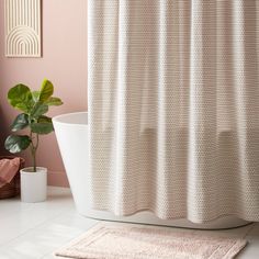 a white bath tub sitting next to a shower curtain in a bathroom with pink walls