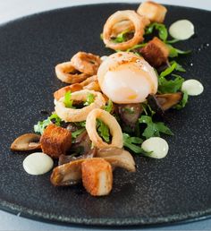 a black plate topped with food on top of a table