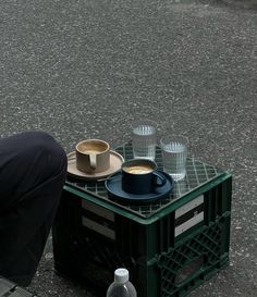 a man kneeling down next to a table with cups on it