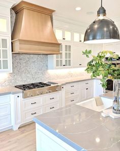 a large kitchen with white cabinets and marble counter tops, an island in the middle