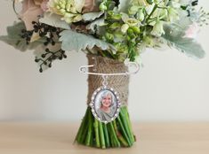 a bouquet of flowers with a photo hanging from the top is shown on a table