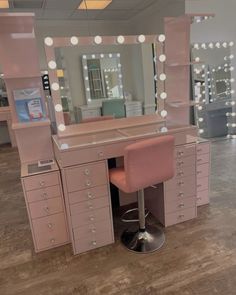 a pink vanity with lights on it and a stool in front of the mirror that is open