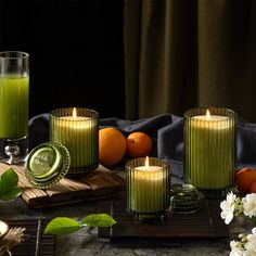 four candles sitting on top of a table next to oranges