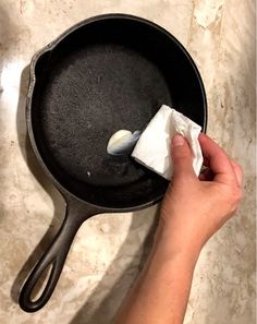 a person cleaning a skillet with a sponge