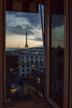 the eiffel tower is lit up at night from an apartment window in paris