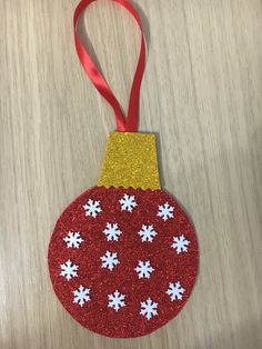 a red ornament with white snowflakes hanging from it's side