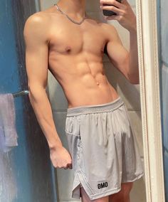 a shirtless man taking a selfie in front of a mirror with his cell phone