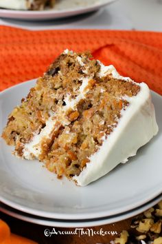 a slice of carrot cake on a white plate with an orange towel in the background