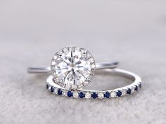 a diamond and blue sapphire engagement ring with matching wedding band in white gold, set on top of a gray background