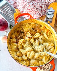 a red pot filled with pasta next to garlic and other ingredients on a counter top