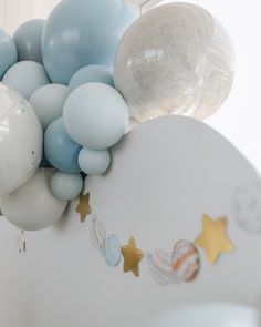 balloons and stars are hanging from the ceiling in front of a wall with a balloon garland on it