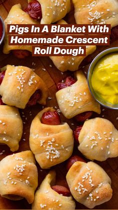 pigs in a blanket with mustard and ketchup on a cutting board next to dipping sauce