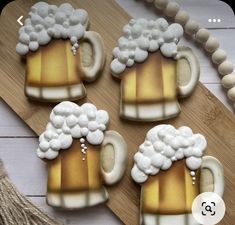 decorated cookies with frosting and beer mugs on a cutting board next to tassels