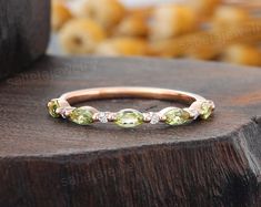 a gold ring with green and white stones on it sitting on top of a piece of wood