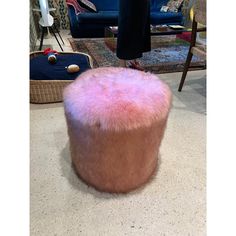 a pink ottoman sitting on top of a white floor next to a blue couch and chair