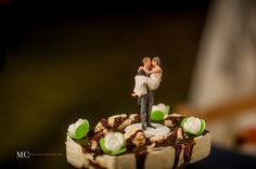 a bride and groom figurine sitting on top of a piece of chocolate cake