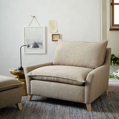 a living room with a chair, ottoman and pictures hanging on the wall above it