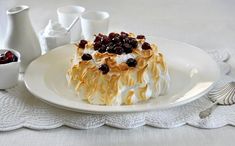 a white plate topped with a dessert covered in whipped cream and cherries on top of a table