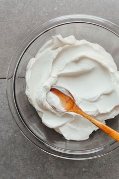 a glass bowl filled with whipped cream and a wooden spoon