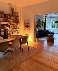 a living room with wooden floors and white walls, an open door leading into the dining area