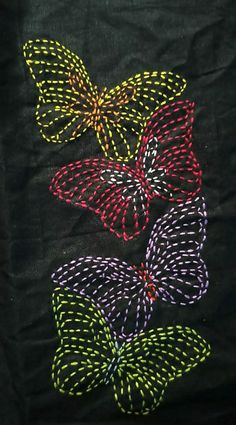 three butterflies on black fabric with yellow, red and green threadwork in the middle