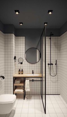 a bathroom with black and white tiles on the walls, a sink, mirror, toilet and shower stall