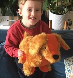 a young boy sitting on a couch holding a stuffed dog