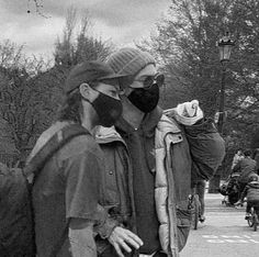 black and white photograph of two people walking down the street with masks on their faces