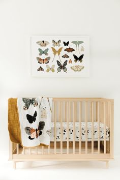 a baby's crib with butterflies on the wall and a framed photo above it