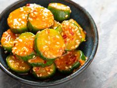 a bowl filled with cucumbers covered in sesame seeds