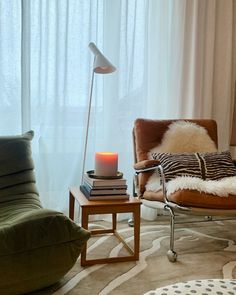 a living room filled with furniture and a lamp on top of a wooden table next to a window