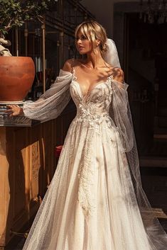 a woman in a wedding dress standing next to a potted plant and wearing a veil