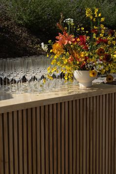 there are many wine glasses lined up on the table with flowers in front of them