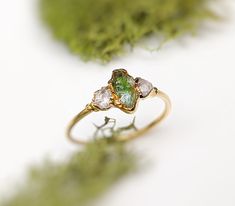 three stone ring sitting on top of green moss