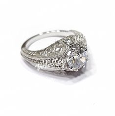 an antique style diamond ring with filigrees on the band and center stone