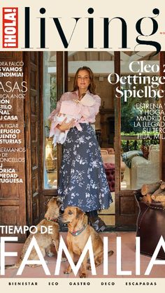 a woman standing in front of a door with two dogs on the cover of a magazine