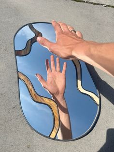 a hand reaching for something in the reflection of a mirror that is on the ground