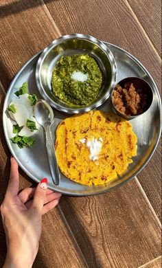 a person is holding a plate with food on it and dipping sauces in bowls