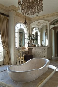 a large bathtub sitting in the middle of a bathroom next to a chandelier