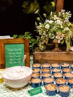 a table topped with lots of cupcakes next to a bowl of whipped cream