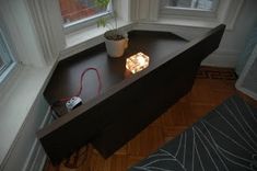 a desk with a plant on it in front of a window and a power strip