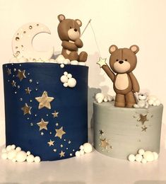 two teddy bears sitting on top of a blue and white cake with stars around it