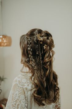 the back of a woman's head with braids and flowers in her hair