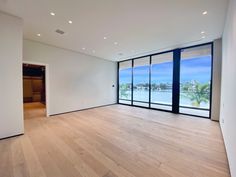 an empty room with wood floors and large windows