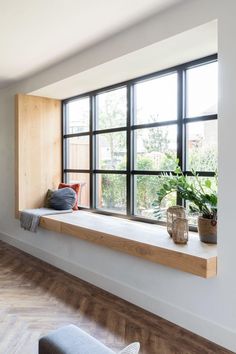 there is a window with some plants on the ledge in front of it and a bench next to it