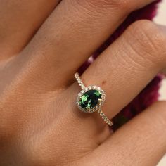 a woman's hand with a green and white diamond ring on top of her finger