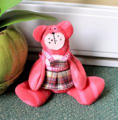 a pink teddy bear sitting next to a potted plant