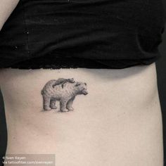 a small bear tattoo on the side of a woman's stomach is shown in black and white