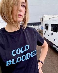 a woman standing in front of a trailer with the words cold blood on her t - shirt