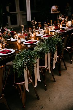 a long table set with place settings and candles for an outdoor wedding reception at night